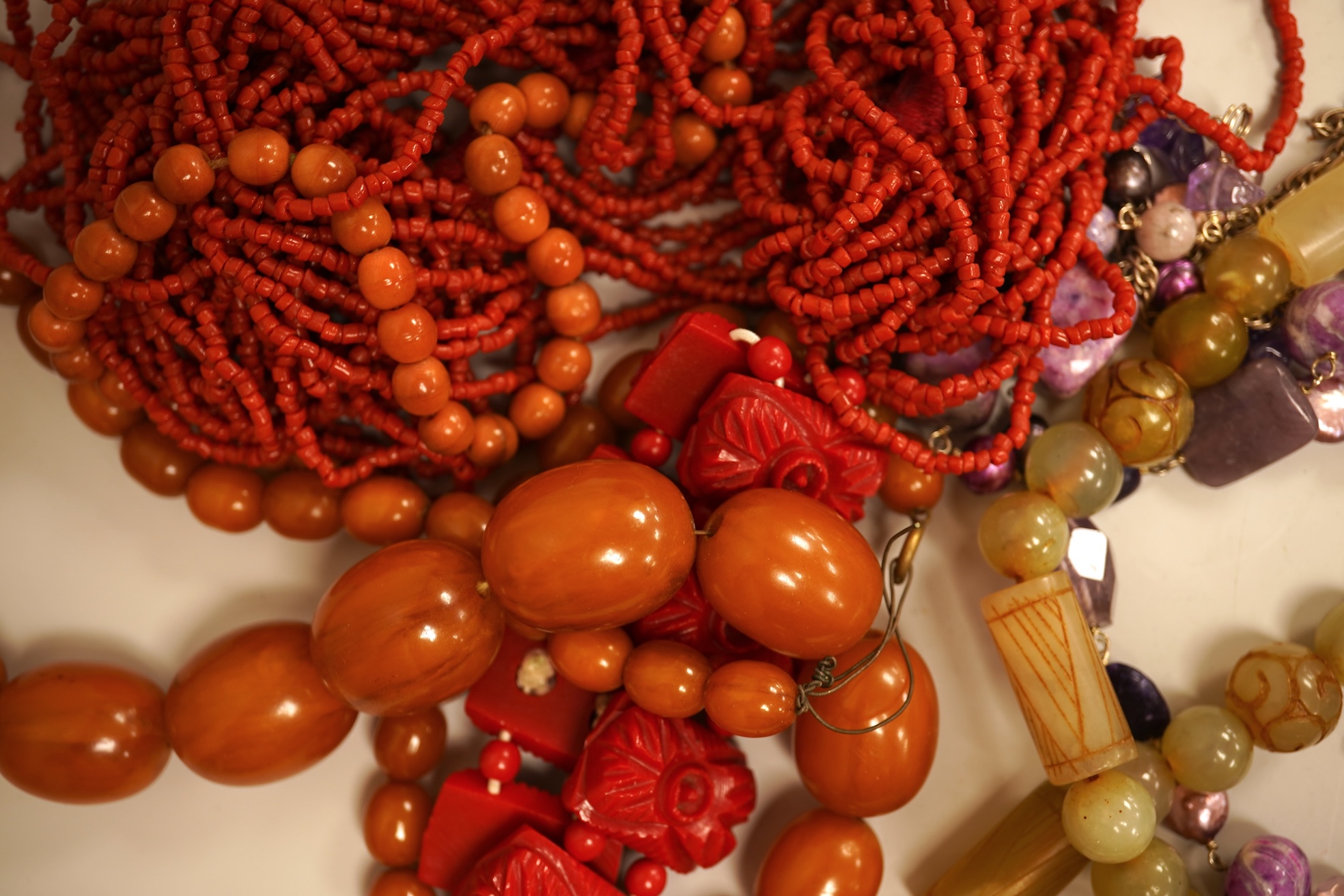 A small group of sundry jewellery including a simulated amber necklace and a multi strand coral bead necklace, etc.